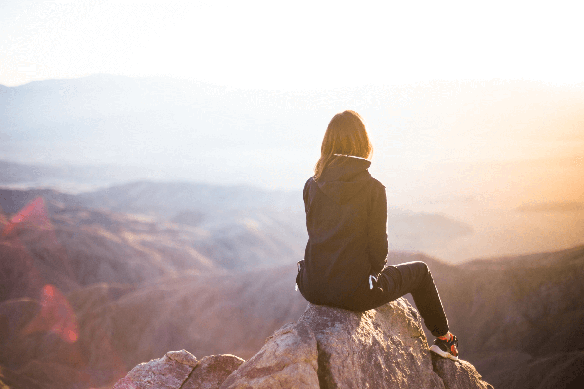 Woman enjoying the outdoors, sitting on a mountaintop