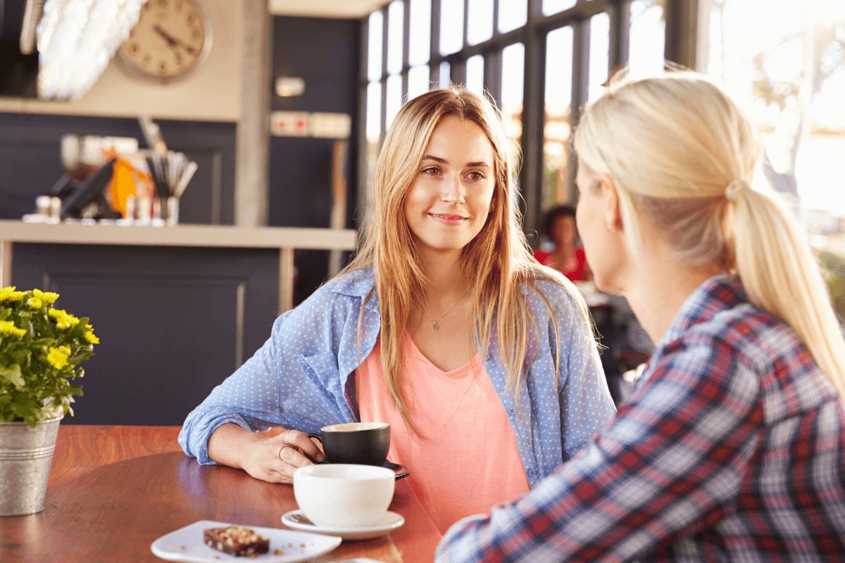 Two women at a coffee shop talking with each other